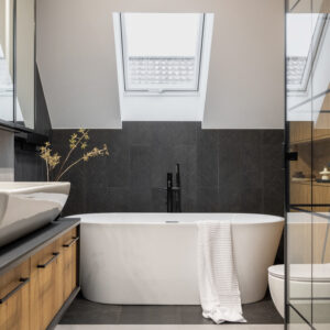 Stylish interior of bathroom with bathtub, shower, towels and other personal bathroom accessories. 