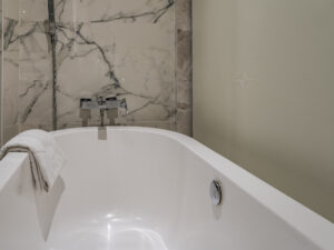 Close-up image of a white acrylic bathtub with a silver faucet. 